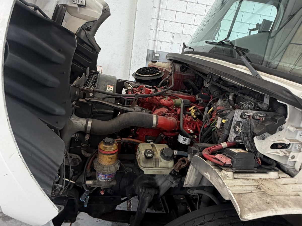 Cummins engine exposed under the tilted cab of a 2016 Freightliner M2 bucket truck