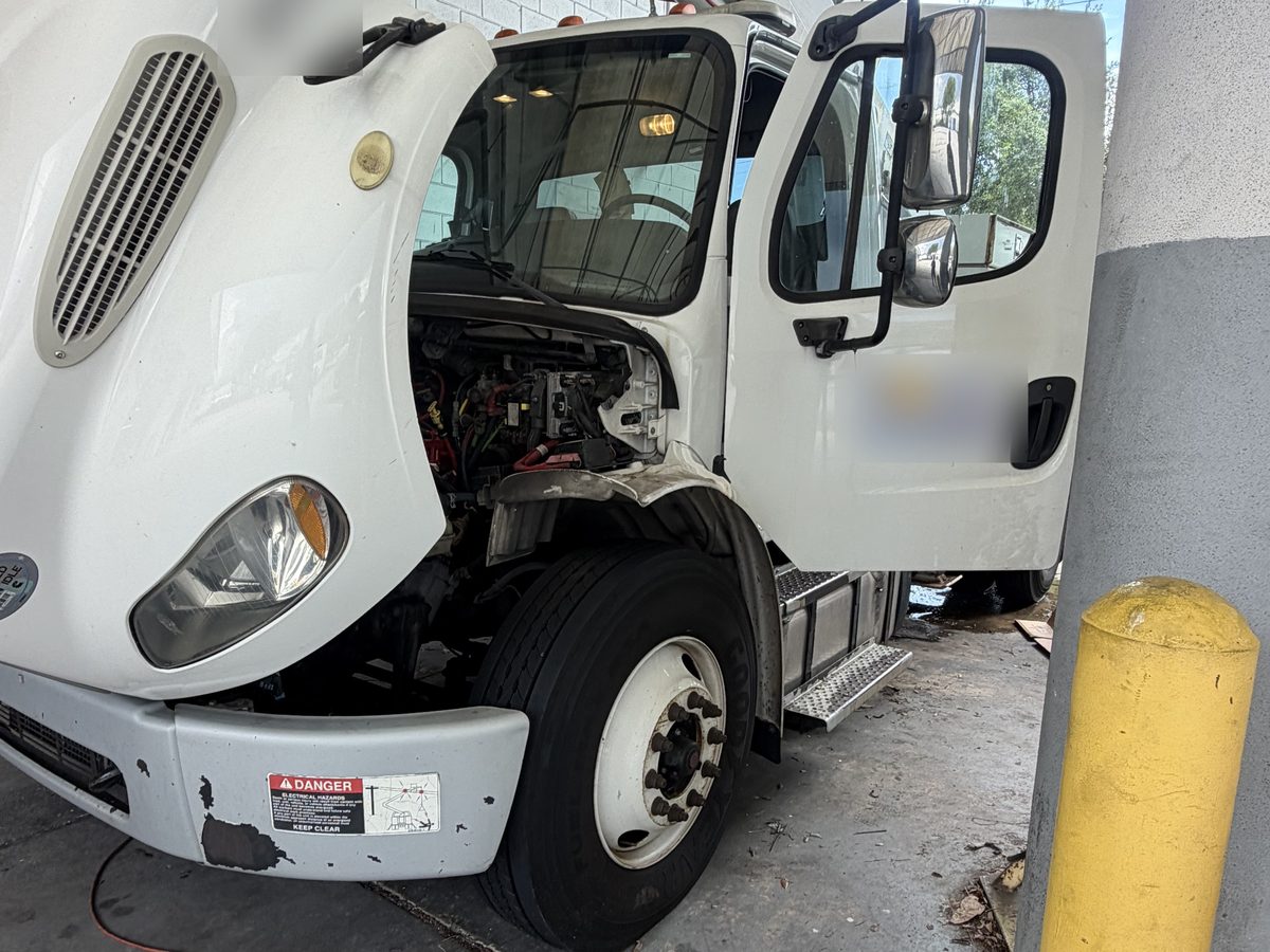 2016 Freightliner M2 bucket truck with the cab tilted forward, engine exposed, during on-site ECM reprogramming