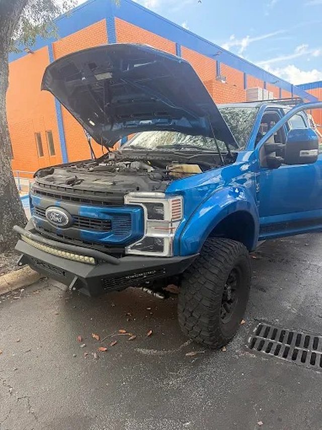 Blue Ford Super Duty, hood open, full tune-up in progress