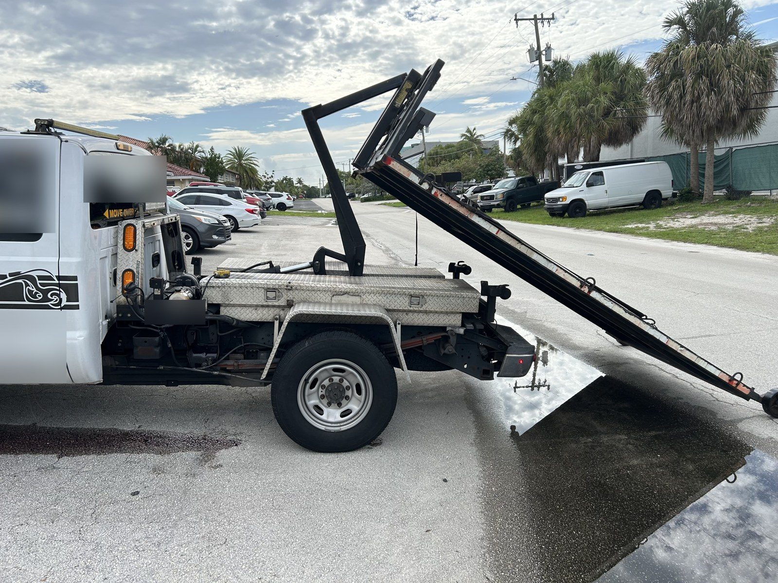 Tow truck with its bed raised during an on-site hydraulic repair